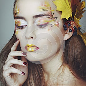 Beautiful girl with autumn make up and leaves on head