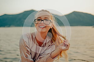 Beautiful girl on the background of the sea and mountains in glasses. Poor eyesight. Teenager smiling