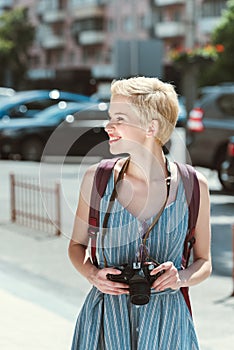beautiful girl with backpack and photo camera walking