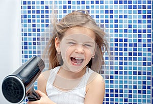 Beautiful girl in the bathroom, blow dry with foams. Little girl