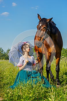 Beautiful girl in a beautiful dress standing next to the horse