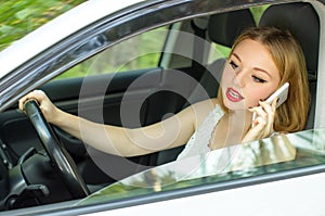 Beautiful girl behind the wheel of a car talking on the phone