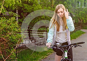 A beautiful girl on a bicycle adjusts her hair