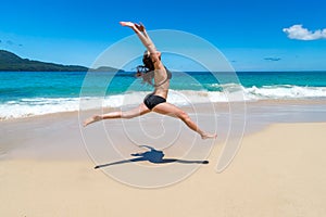 Beautiful girl in bikinis jumping on tropical beach