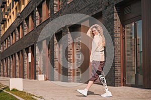 Beautiful girl with bionic prosthesis walking down the street in summer