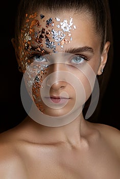 beautiful girl on a black background. beauty portrait close-up. Gold particles on the face