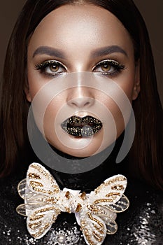 Beautiful girl with black creative art make-up and gold accessories. Beauty face.