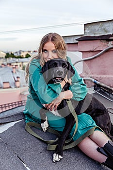 Beautiful girl with black dog on the roof at sunset in summer