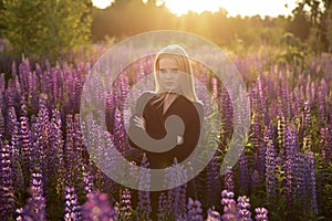 Beautiful girl in a black dress on a lupine field