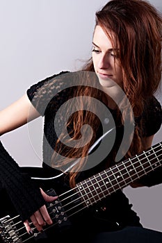 Beautiful girl in black plays bass guitar