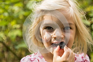 Beautiful Girl with Blackberry in the Garden.