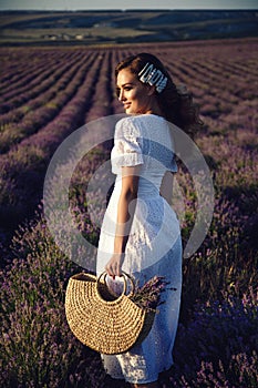 Beautiful girl with blond hair in elegant clothes posing in summer flowering lavender field