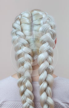 Beautiful girl with blonde hair, hairdresser weaves a braid close-up, in a beauty salon.