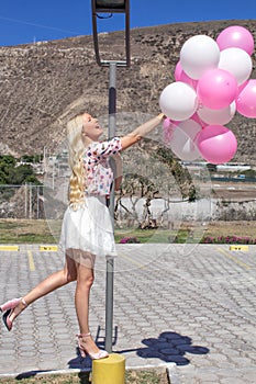 Beautiful girl, the blonde is standing on a light bulb and holds a lot of balloons.