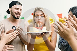 Beautiful Girl blowing the birthday cake in the party with friends clap her birthday celebration song