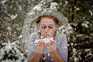 Beautiful girl blowing snow off her hands. Outdoor winter portrait.