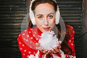 Beautiful girl blowing to the snow in hands during christmas celebration - christmas and new year concept