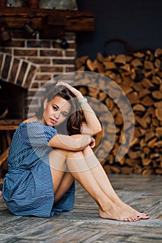 Beautiful girl in blue dress sit barefoot on floor