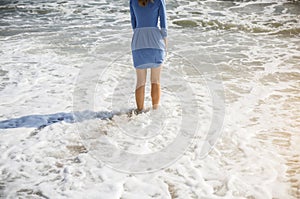 Beautiful girl in blue dress is walking on the beach. Amazing summer photo. Woman near the sea. Holiday travel concept. Slim legs