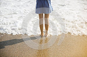 Beautiful girl in blue dress is walking on the beach. Amazing summer photo. Woman near the sea. Holiday travel concept. Slim legs