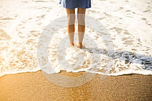 Beautiful girl in blue dress is walking on the beach. Amazing summer photo. Woman near the sea. Holiday travel concept. Slim legs