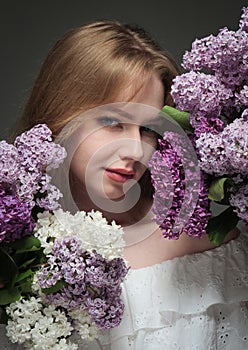 beautiful girl with blue eyes with a bouquet of lilacs on a black background in the studio