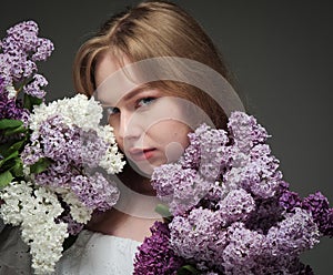 beautiful girl with blue eyes with a bouquet of lilacs on a black background in the studio