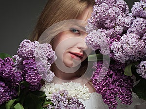 beautiful girl with blue eyes with a bouquet of lilacs on a black background in the studio