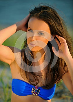 Beautiful girl in blue swimsuit posing on the beach