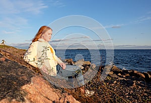 Beautiful girl body positive looking ahead on rocks seaside background in autumn season