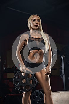 Beautiful girl bodybuilder , execute exercise with dumbbells, in dark gym