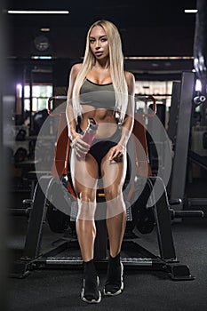 Beautiful girl bodybuilder , execute exercise with dumbbells, in dark gym