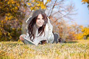 Beautiful girl with book lying on grass