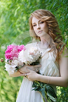 Beautiful girl with a bouquet of peonies in hands