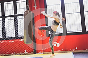 Beautiful girl boxing against punching bag (intentionally blurred)