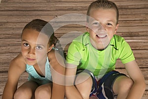 Beautiful girl and boy sitting on wood floor looking up