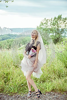 Beautiful girl bride blonde in gothic style with a bouquet in hand in summer