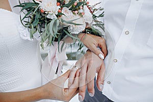 Beautiful girl bride in wedding white dress puts on the groom`s finger the wedding gold ring.
