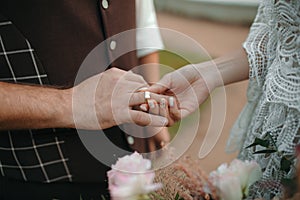 Beautiful girl bride in wedding white dress puts on the groom`s finger the wedding gold ring