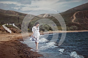 Beautiful girl, bride, in white dress, barefoot, runs on the beach, on the water and laughs.