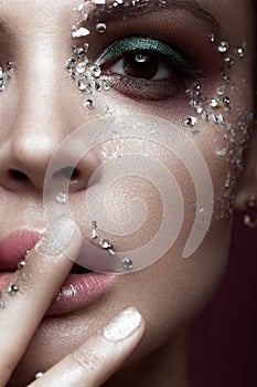 Beautiful girl with bright color makeup and crystals on the face. Close-up portrait.