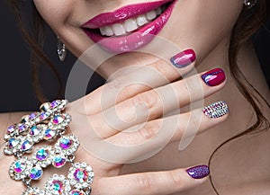 Beautiful girl with a bright evening make-up and pink manicure with rhinestones. Nail design. Beauty face.