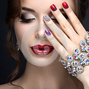 Beautiful girl with a bright evening make-up and red manicure with rhinestones. Nail design. Beauty face.