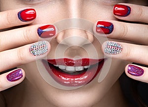 Beautiful girl with a bright evening make-up and red manicure with rhinestones. Nail design. Beauty face. photo