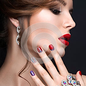 Beautiful girl with a bright evening make-up and red manicure with rhinestones. Nail design. Beauty face.