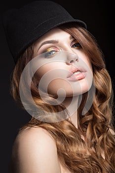 Beautiful girl with bright makeup and curls in a hat. Beauty face.