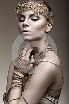 Beautiful girl with a bronze skin, pale makeup and unusual accessories. Art beauty image. Beauty face.