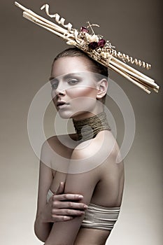 Beautiful girl with a bronze skin, pale makeup and unusual accessories. Art beauty image. Beauty face.