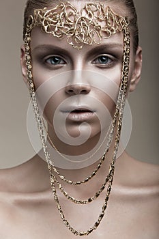 Beautiful girl with a bronze skin, pale makeup and unusual accessories. Art beauty image. Beauty face.