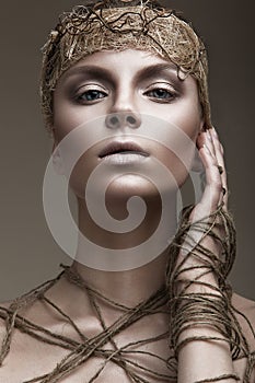 Beautiful girl with a bronze skin, pale makeup and unusual accessories. Art beauty image. Beauty face. photo